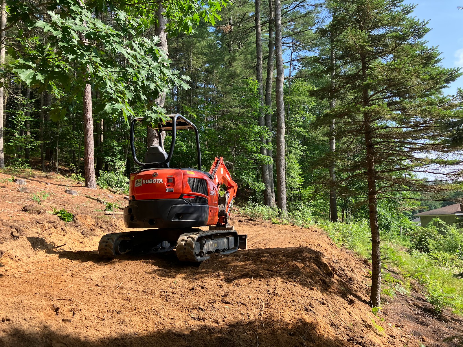 Compact excavator working on a wooded hillside